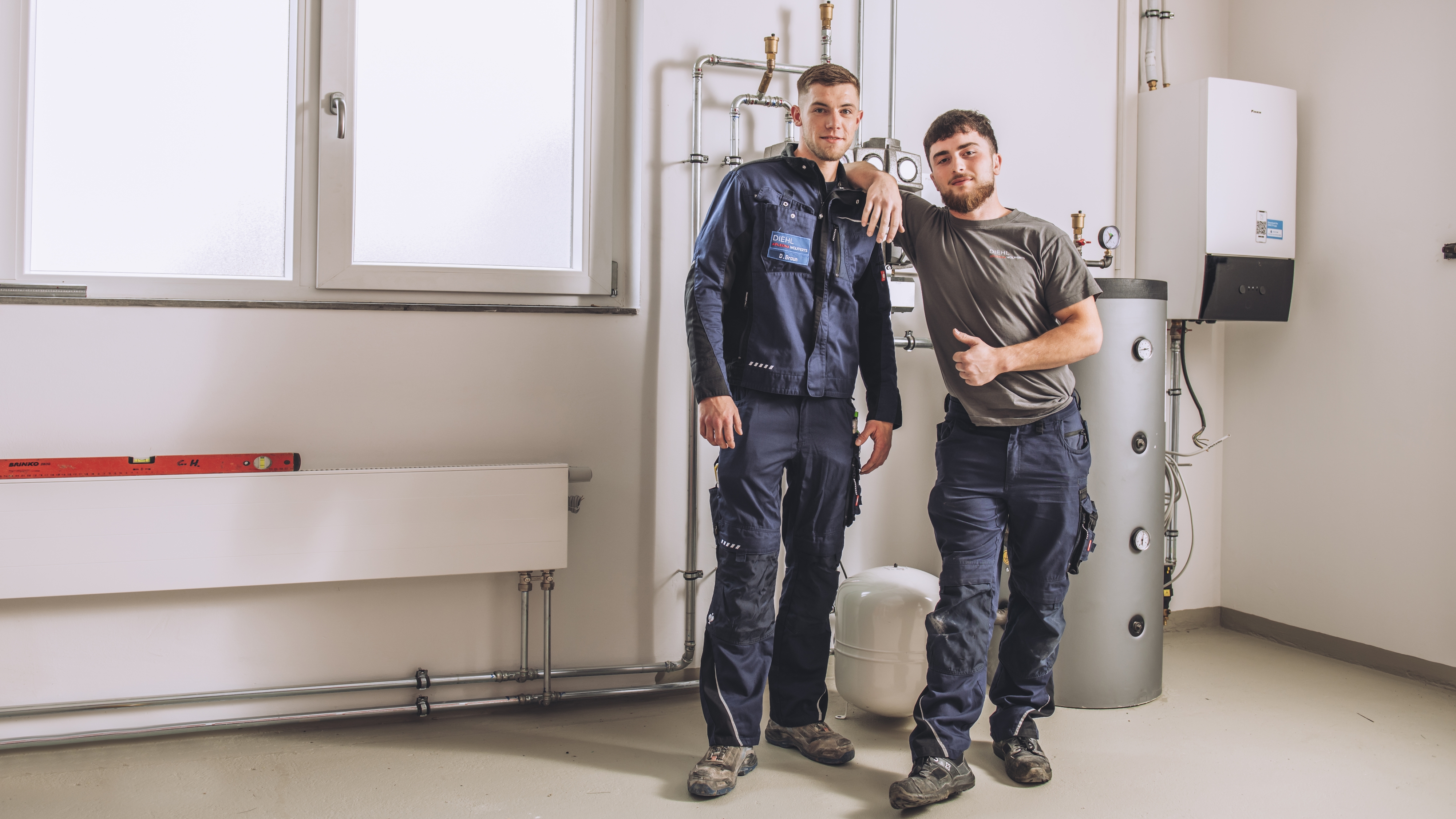 Ausbildung zum Anlagenmechaniker Sanitär-, Heizungs- und Klimatechnik: Dein Einstieg ins SHK-Handwerk: zukunftssicher und praxisnah Zwei coole, junge Azubis vor einer Heizungsanlage