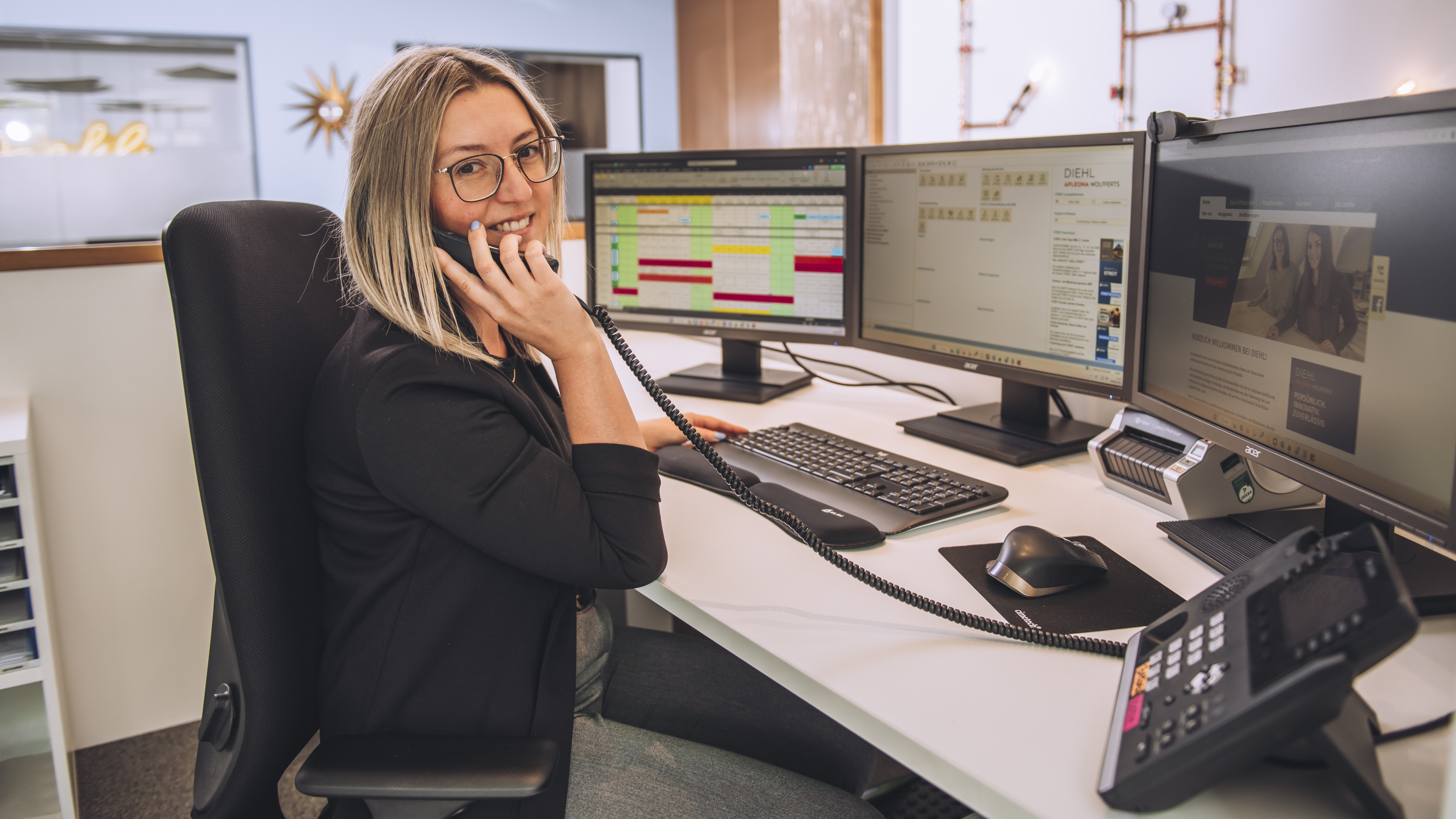 Ausbildung zur Kaufmann/-frau für Büromanagement: Die Schaltzentrale im Büroalltag Junge Mitarbeiterin sitzt an einem Schreibtisch und telefoniert