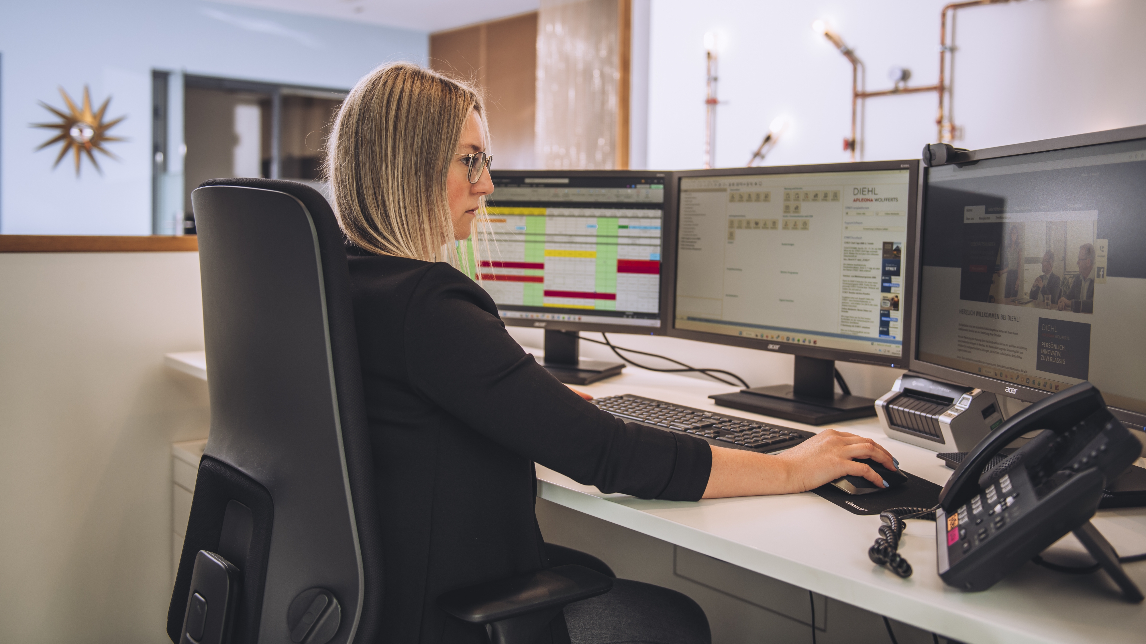 Ausbildung Industriekaufmann/-frau: Der kaufmännische Allrounder in der Gebäudetechnik Junge Mitarbeiterin sitzt konzentriert vor einem Schreibtisch mit drei Monitoren